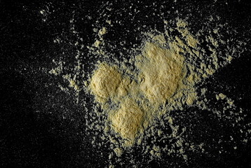 Corn flour pile isolated on black texture, top view