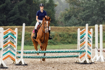 Eventing: equestrian rider jumping over an a barrier fence obstacle.