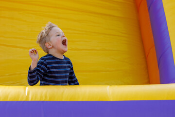 Little boy having fun in inflatable castle playground. The child is naughty and shouts loudly....