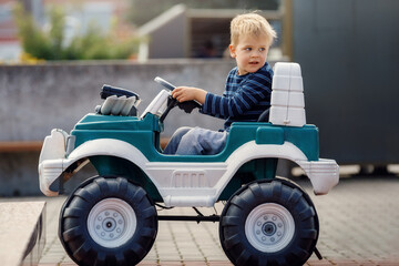 Young boy riding in battery powered car. The concept of a happy childhood.