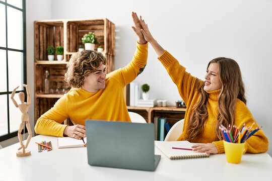 Young caucasian couple high five raised up hands having online art class at home