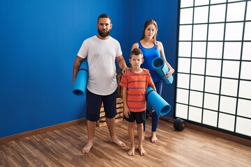 Fototapeta na wymiar Family of three holding yoga mat thinking attitude and sober expression looking self confident