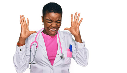 Young african american woman wearing doctor uniform and stethoscope celebrating mad and crazy for...