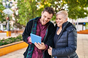 Naklejka premium Mother and son smiling confident using touchpad at park