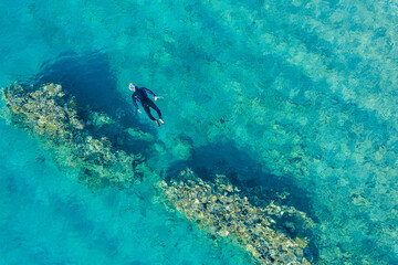 A man with a diving suit, snorkeling, on the coral reef in Eilat, Israel.