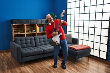 Senior man playing electrical guitar at home