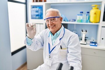 Senior man wearing scientist uniform holding sample at laboratory