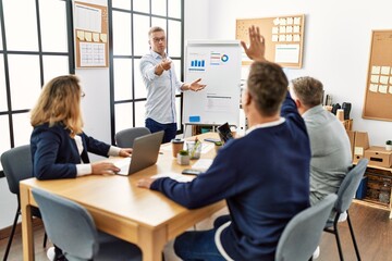 Group of middle age business workers listening boss conference during meeting at the office.