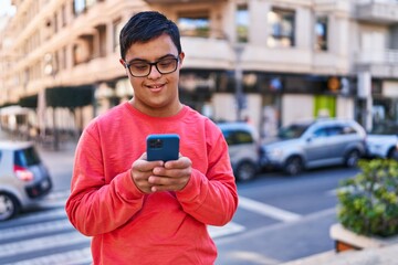 Down syndrome man smiling confident using smartphone at street