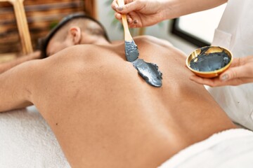 Fototapeta premium Young hispanic man relaxed having skin back treatment at beauty center