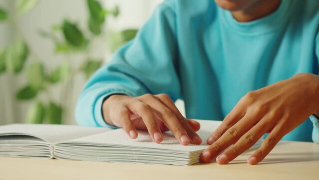 African American man reading braille book close-up. Poorly seeing teenager learning to read, home education for people with disabilities, touching letters on sheet of paper.