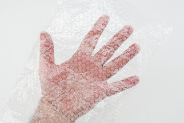 Male hand in plastic wrap with pimples. Man's hand in a plastic bag. Male hand inside a transparent wrap bag. Hand of a male wrapped in plastic film. Protection polyethylene wrap with bubble.