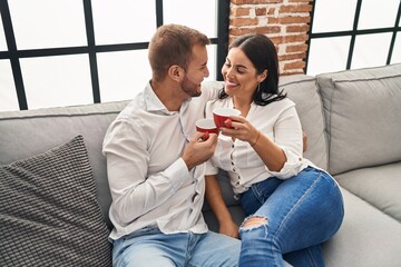 Man and woman couple drinking coffee hugging each other at home