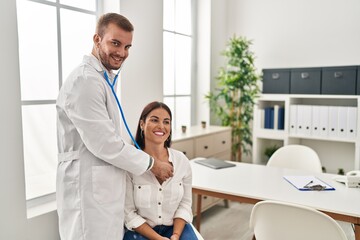 Man and woman doctor and patient auscultating heart having medical consultation at clinic