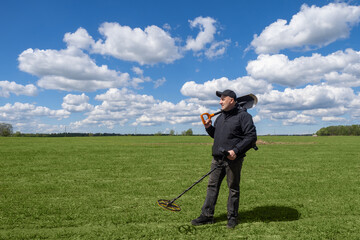 Man with metal detector. Human is standing with shovel and metal finder. Treasure seeker on green...