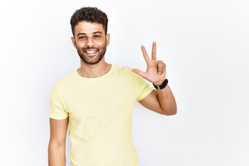 Arab young man standing over isolated background showing and pointing up with fingers number three while smiling confident and happy.