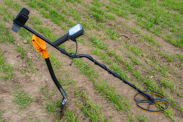 Fototapeta na wymiar Digging equipment. Shovel and metal detector on ground. Digger equipment without anyone. Modern magnetic metal detector with display. Treasure search device. Concept selling metal detectors