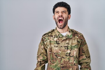 Arab man wearing camouflage army uniform angry and mad screaming frustrated and furious, shouting...