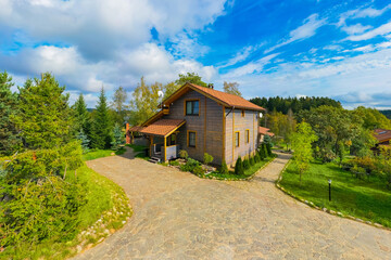 Fototapeta na wymiar Vacation home. Two-story wooden house. Country cottage view from copter. Stone paved path in front of cottage. Country hotel in summer weather. Suburban house and blue sky. Scandinavian style house