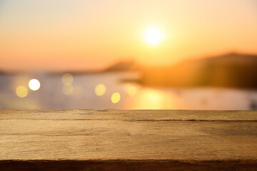 Empty wooden table over sunset blurred background. Summer vacation mock up design and product...