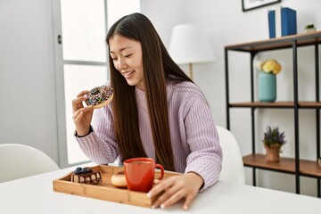 Young chinese girl having breakfast sitting on the table at home.