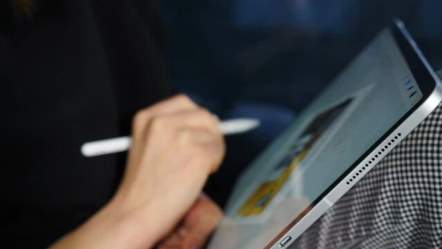 Creative graphic designer working in office on tablet holding stylus. Closeup. Architect designer working with laptop tablet, creative designer drawing and colouring while making digital illustration