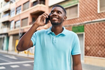 Fototapeta premium Young african american man smiling confident talking on the smartphone at street
