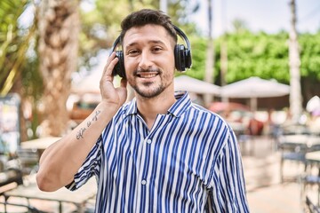 Young handsome man using headphones at park