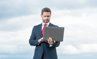 man in suit using laptop on sky background