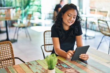 Young chinese woman using touchpad sitting on table at restaurant