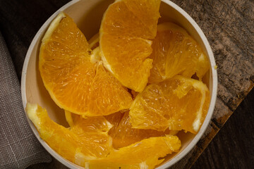 Fototapeta na wymiar Sliced ​​orange served in a clay bowl on rustic wooden table.