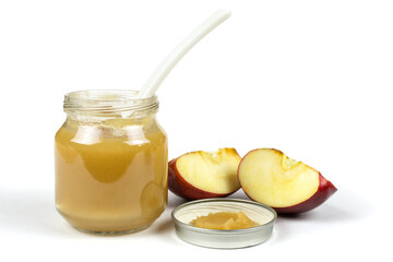 Baby food. A glass jar with baby apple puree with a spoon, a gooseberry and an apple slice on a white isolated background. The first fruit lure.