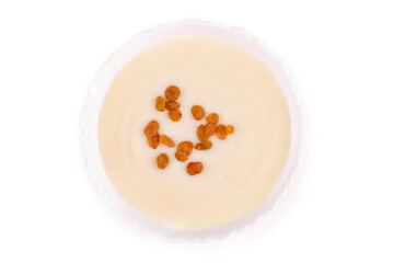 Semolina porridge with raisins in a plate on a white isolated background. View from above.