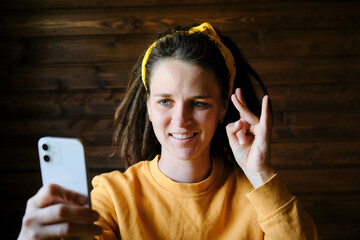 Young European woman with dreadlocks talks over video link using sign language and smiles. Body...