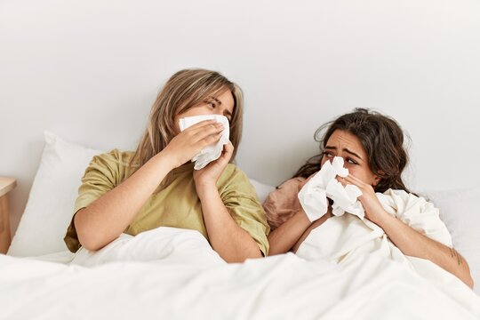 Young ill couple using napkin lying on the bed at home.