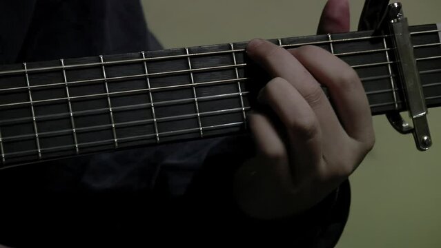 Male Guitarist playing a Classical Guitar with Clamp Capo, Young Male Classical Musician with a Guitar. Close Up.  