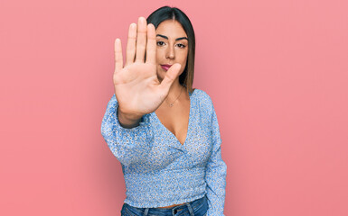 Young hispanic woman wearing casual clothes doing stop sing with palm of the hand. warning...