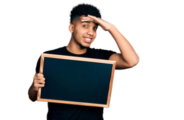 Young african american man holding blackboard stressed and frustrated with hand on head, surprised and angry face