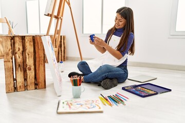 Fototapeta na wymiar Young latin woman make photo to draw sitting on floor at art studio