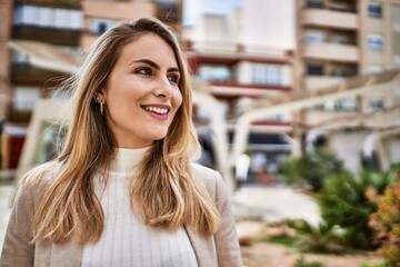 Young blonde woman smiling confident at street