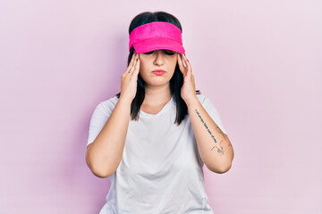 Young hispanic woman wearing sportswear and sun visor cap suffering from headache desperate and stressed because pain and migraine. hands on head.