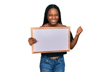 Young african american woman holding empty white chalkboard screaming proud, celebrating victory and success very excited with raised arms
