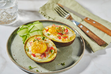 Avocado baked with egg, ham, tomatoes and cheese. Keto lunch recipe. After baking