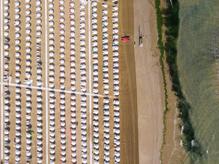 Italy, June 2022: aerial view of beach umbrellas that draw particular, colorful and relaxing geometries and textures