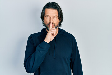 Middle age caucasian man wearing casual sweatshirt asking to be quiet with finger on lips. silence and secret concept.