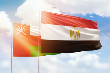 Sunny blue sky and flags of egypt and oman