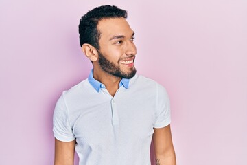 Hispanic man with beard wearing casual white t shirt looking to side, relax profile pose with natural face and confident smile.
