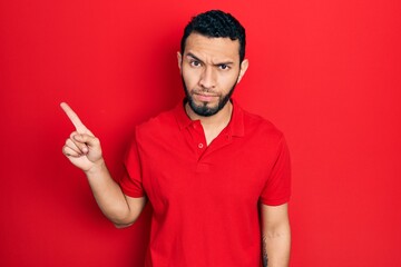 Hispanic man with beard pointing with fingers to the side skeptic and nervous, frowning upset...