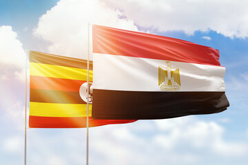 Sunny blue sky and flags of egypt and uganda