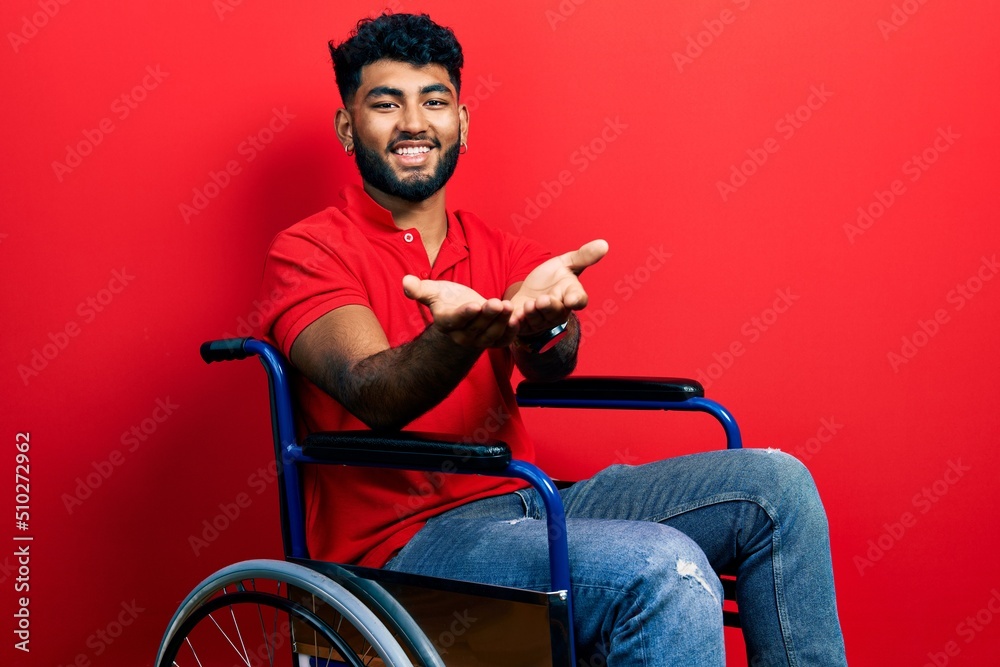 Canvas Prints Arab man with beard sitting on wheelchair smiling with hands palms together receiving or giving gesture. hold and protection